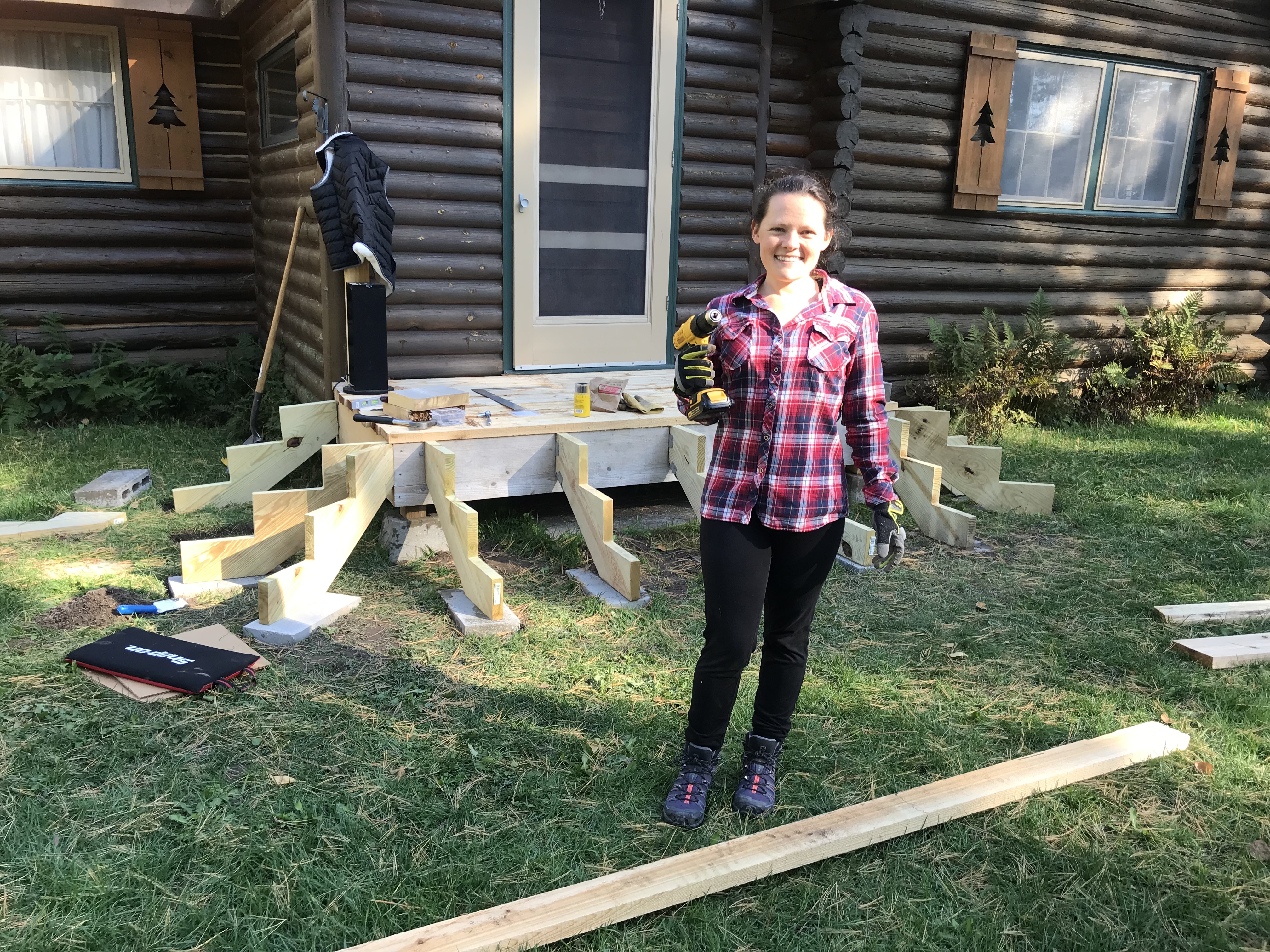 Sara with a drill in front of the cabin
